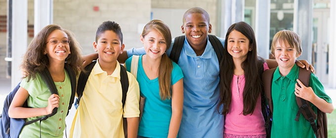 group os diverse students in school hallway smiling at camera